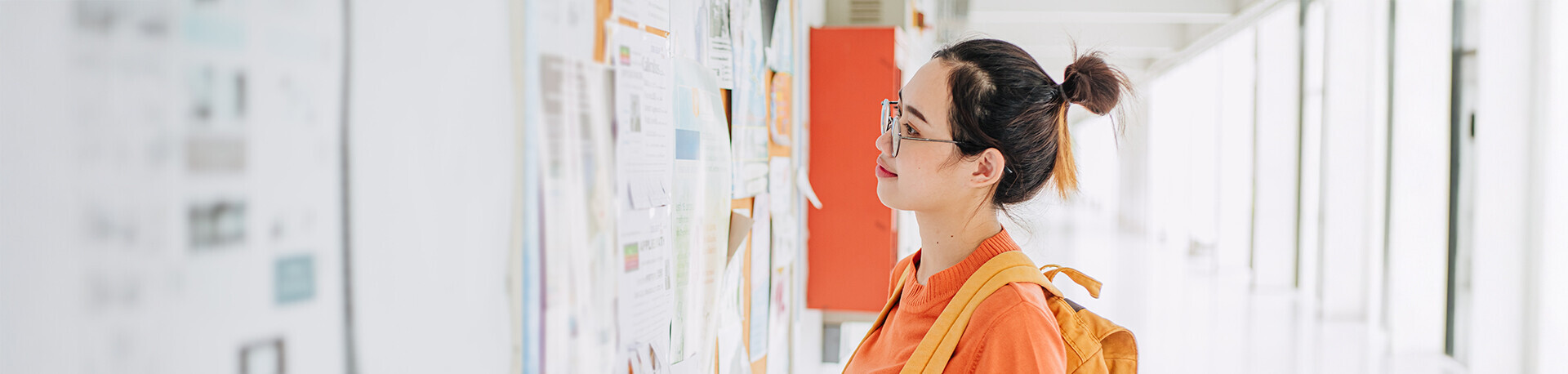Junge Frau mit Rucksack vor einem Whiteboard