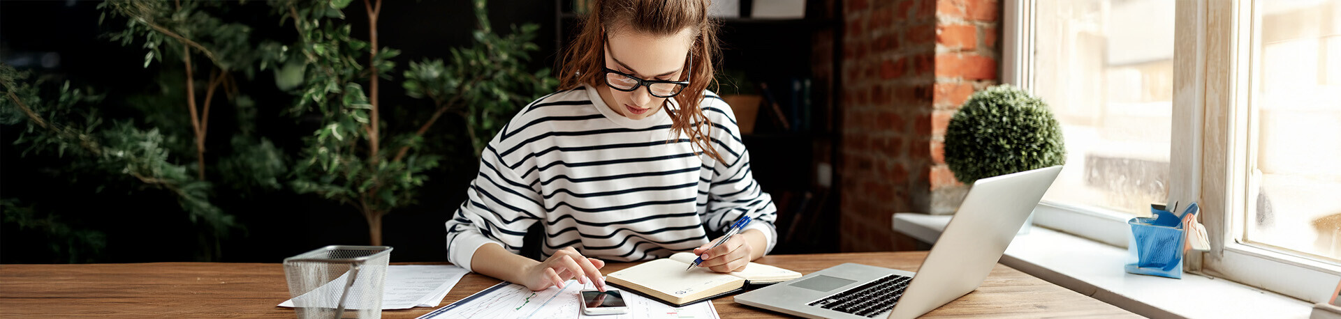 Junge Frau sitzt vor einem Buch und tippt in einen Taschenrechner