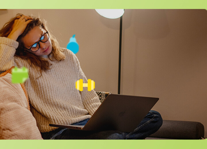 Junge Frau sitzt erschöpft auf dem Sofa und blickt in einen Laptop