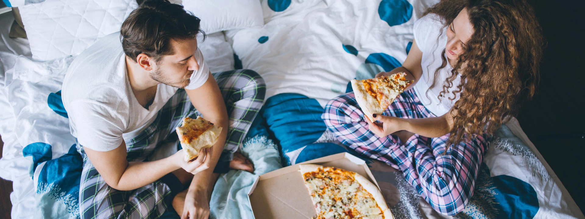 Paar isst Pizza im Bett
