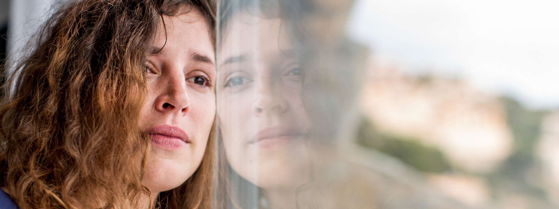 Junge Frau sieht traurig aus dem Fenster