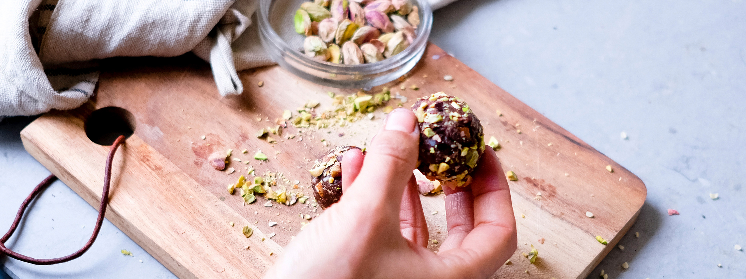Hand hält Energiekugel aus Nüssen und Früchten