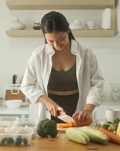 Junge Frau schneidet Gemüse auf einem Schneidebrett
