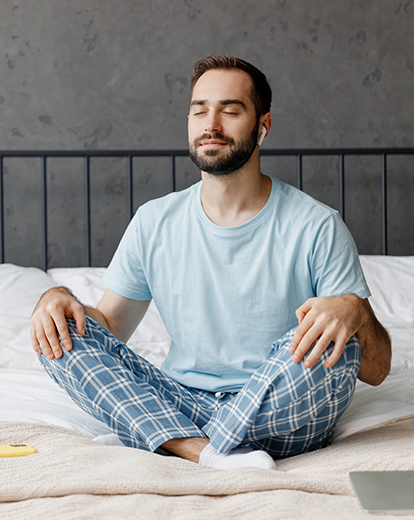 Mann auf seinem Bett meditiert