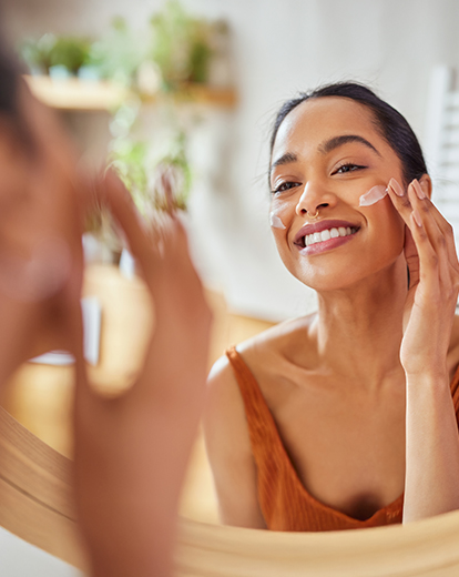 Frau verwendet Gesichtscreme auf ihrer Wange