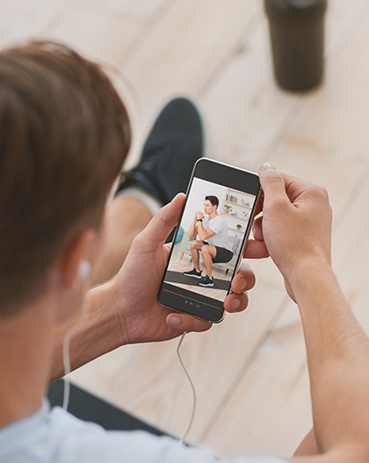 Mann schaut sich ein Workout auf seinem Handy an