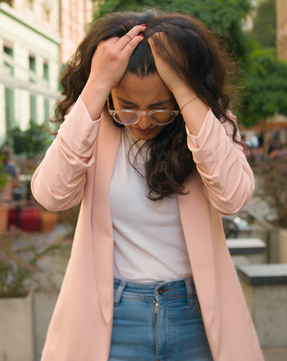 Frau auf der Straße hält ihren Kopf mit beiden Händen
