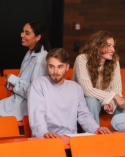 Junger Student sitzt in einer Gruppe von Menschen und schaut abwesend