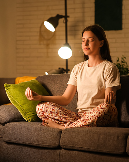 Junge Frau sitzt im Schneidersitz auf einem Sofa