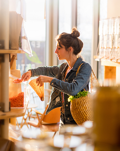 Frau in einem Unverpacktladen füllt eine Tüte auf