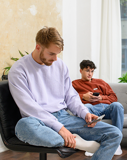 Drei junge Männer sitzen auf einer Couch und schauen in ihre Handys