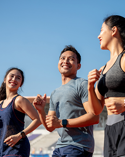 Drei junge Menschen machen gemeinsam Sport und lachen dabei.