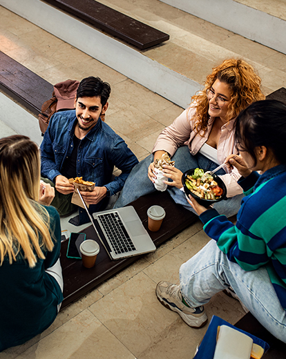 Gruppe an Studenten im Kreis beim Mittagessen