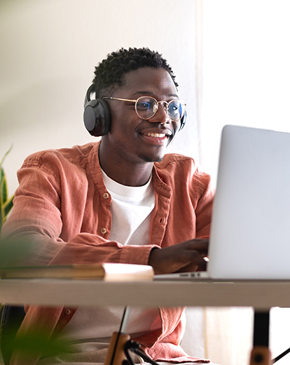 Mann sitzt vor einem Laptop und lacht