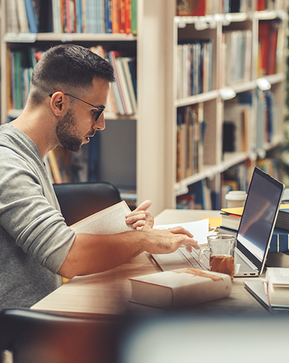 Junger Mann an Tisch in einer Bibliothek