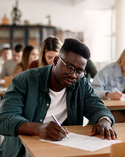 Student in einer Prüfung schreibt auf ein Blatt