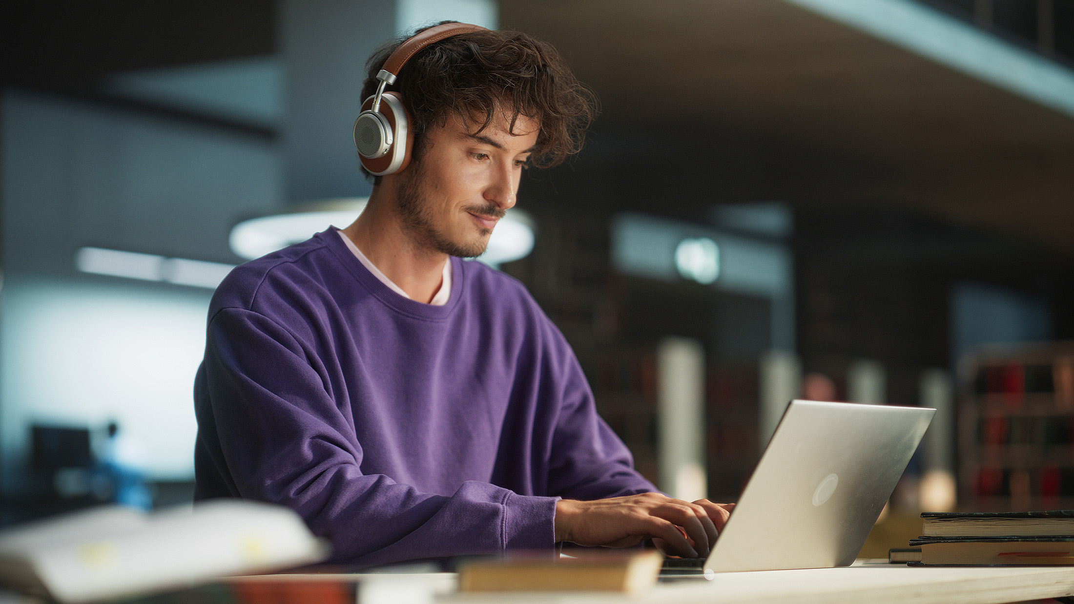 Ein junger Mann sitzt konzentriert an einem Laptop.