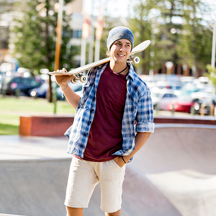 Junger Mann mit Skateboard auf der Schulter