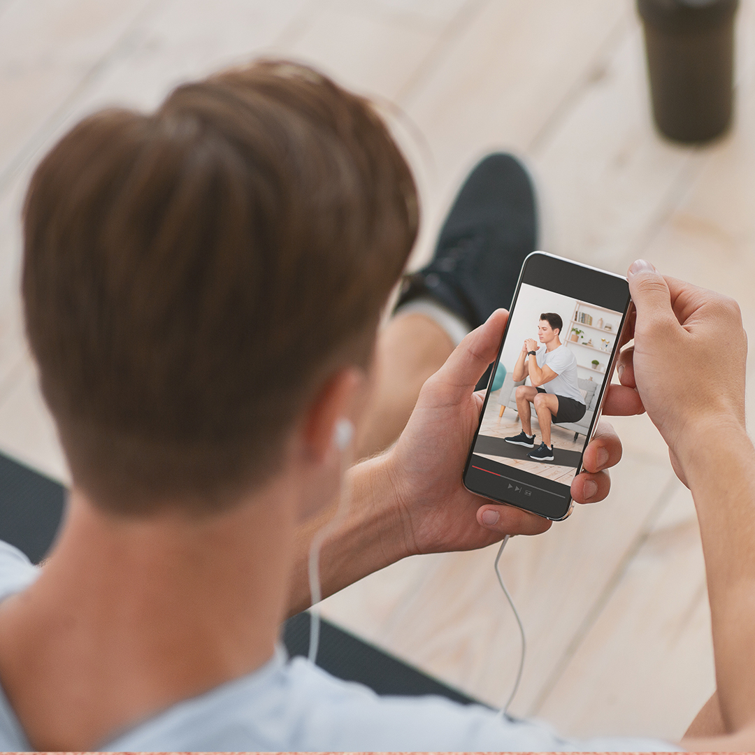 Mann schaut sich ein Workout auf seinem Handy an