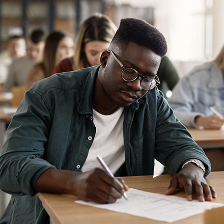 Student in einer Prüfung schreibt auf ein Blatt